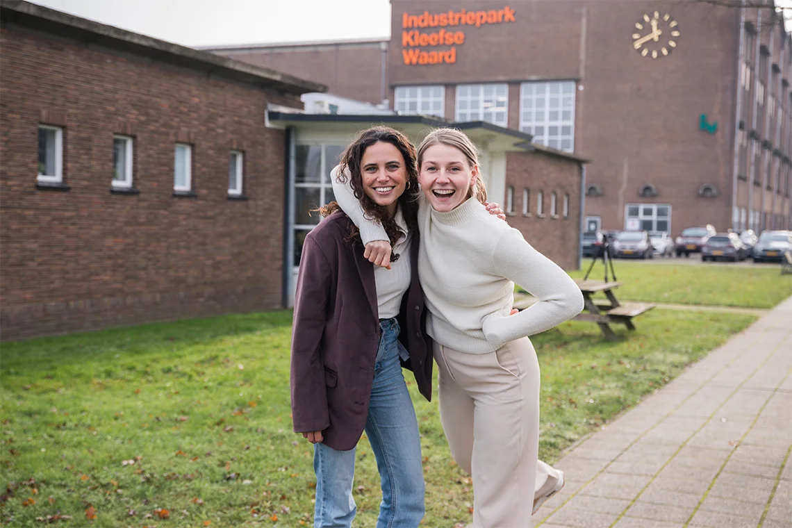 twee blije vrouwen die elkaar met een arm omhelsen