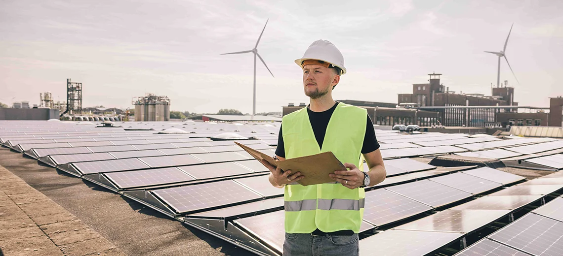 man met zonnepanelen en windmolens op de achtergrond