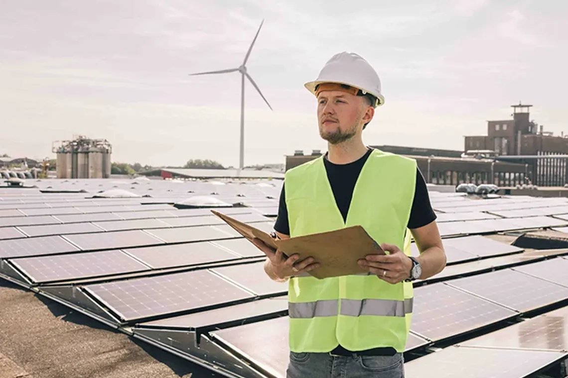 man met zonnepanelen en windmolens op de achtergrond